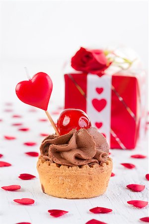 cup-cake with cherry in front of gift box on white wooden background. Valentines day concept Foto de stock - Super Valor sin royalties y Suscripción, Código: 400-08494199