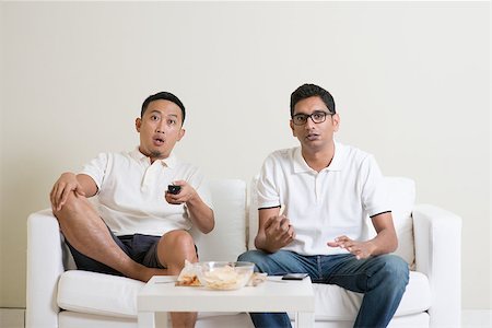 Group of men sitting on sofa watching sport together at home. Stock Photo - Budget Royalty-Free & Subscription, Code: 400-08494558