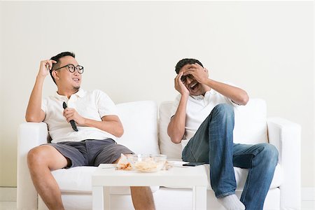 Men sitting on couch watching movie on television together at home. Stock Photo - Budget Royalty-Free & Subscription, Code: 400-08494565