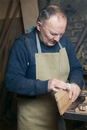 One man sandpaper grinds wood product in a workshop on the table Fotografie stock - Microstock e Abbonamento, Codice: 400-08494731