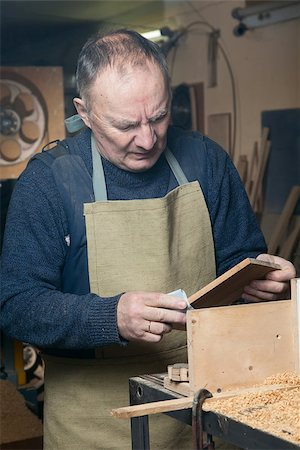 One man sandpaper grinds wood product in a workshop on the table Fotografie stock - Microstock e Abbonamento, Codice: 400-08494732