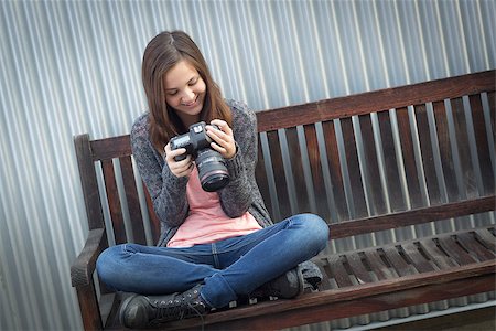 Young Girl Photographer Sitting on Bench Looking at Back of Camera. Stock Photo - Budget Royalty-Free & Subscription, Code: 400-08494937