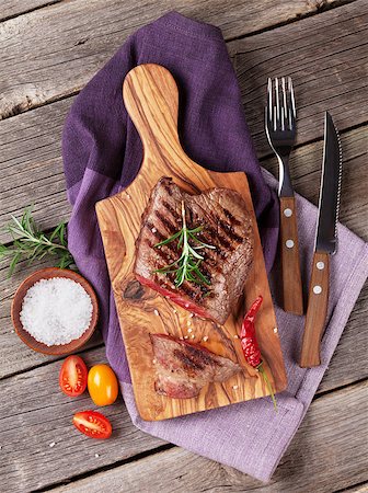 simsearch:400-08495308,k - Grilled beef steak with rosemary, salt and pepper on wooden table. Top view Stockbilder - Microstock & Abonnement, Bildnummer: 400-08495317