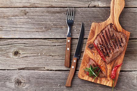 fork and knife on red - Grilled beef steak with rosemary, salt and pepper on wooden table. Top view with copy space Foto de stock - Super Valor sin royalties y Suscripción, Código: 400-08495322