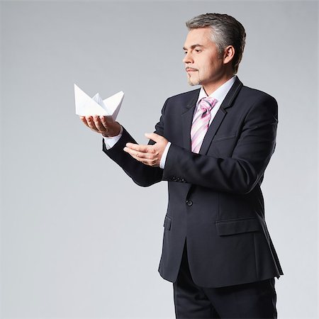 Portrait of businessman holding paper boat. The concept idea Stock Photo - Budget Royalty-Free & Subscription, Code: 400-08495950