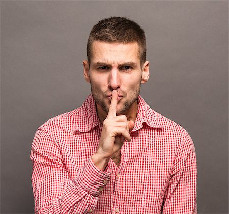 simsearch:400-04238180,k - Man making a shushing gesture with his finger to his lips and asking for silence isolated on grey background. Stockbilder - Microstock & Abonnement, Bildnummer: 400-08496148