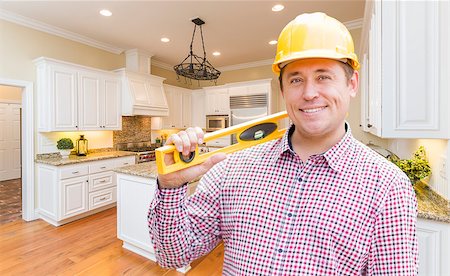 Smiling Contractor with Level Wearing Hard Hat Standing In Custom Kitchen. Stock Photo - Budget Royalty-Free & Subscription, Code: 400-08496912