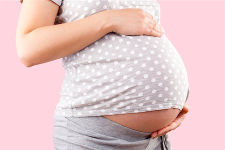 simsearch:400-04859723,k - Pregnant beautiful woman touching big belly isolated on pink background. Pregnancy and motherhood. Fotografie stock - Microstock e Abbonamento, Codice: 400-08497477