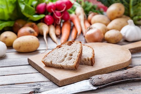 simsearch:400-07982459,k - Freshly cut bread on chopping board with organic vegetables on wooden background Foto de stock - Super Valor sin royalties y Suscripción, Código: 400-08498207