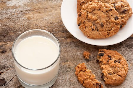 stockarch (artist) - Milk and cookies in childhood tradition with a glass of farm fresh creamy milk and plate of choc chip cookies with one broken one on the old rustic wooden table Stock Photo - Budget Royalty-Free & Subscription, Code: 400-08505316