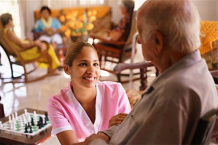 diego_cervo (artist) - Old people in geriatric hospice: young attractive hispanic woman working as nurse takes care of a senior man on wheelchair. She talks with him then goes away to help other patients Fotografie stock - Microstock e Abbonamento, Codice: 400-08507323