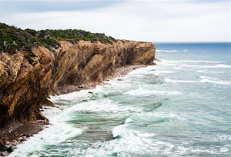 Waves splashing against eroding muddy coastline showing diagonal strata layers, under overcast sky, in Newfoundland, Canada. Fotografie stock - Microstock e Abbonamento, Codice: 400-08500656