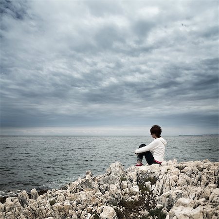 Lonely Woman Sitting at Stormy Sea. Toned and Desaturated Photo with Copy Space. Solitude Concept. Fotografie stock - Microstock e Abbonamento, Codice: 400-08503140