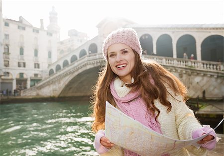 simsearch:400-08530001,k - Ultimate getaway shortcut - start New Year going on Carnival in Venice, Italy. Happy young woman tourist in white sweater holding map in the front of Rialto Bridge and looking on Grand Canal Stockbilder - Microstock & Abonnement, Bildnummer: 400-08530007