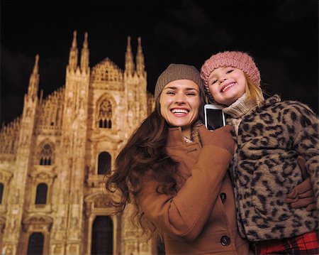 simsearch:400-08341864,k - Family holidays in style. Happy mother and daughter talking smartphone in the front of Duomo in Milan, Italy in the evening Fotografie stock - Microstock e Abbonamento, Codice: 400-08530931