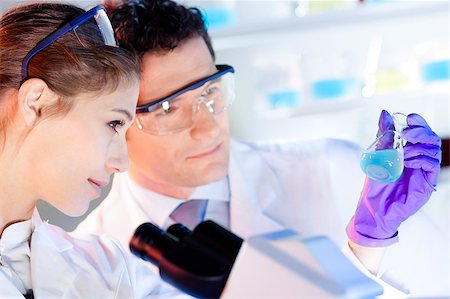 Life science laboratory. Attractive young PhD sscientist observing the blue indicator color shift after the solution  destillation. Stock Photo - Budget Royalty-Free & Subscription, Code: 400-08532099