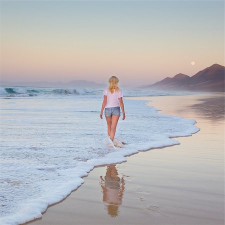 Woman walking on sandy beach in sunset. Waves sweeping away her traces in sand. Beach, travel, concept. Copy space. Square composition. Stock Photo - Budget Royalty-Free & Subscription, Code: 400-08532152