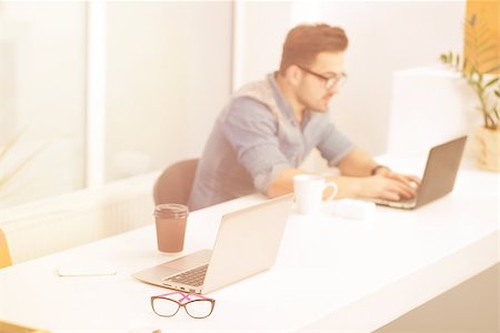 simsearch:400-08161788,k - Freelance man working on laptop computer and drinking coffee or tea in office. Handsome man in glasses typing. Foto de stock - Super Valor sin royalties y Suscripción, Código: 400-08533315