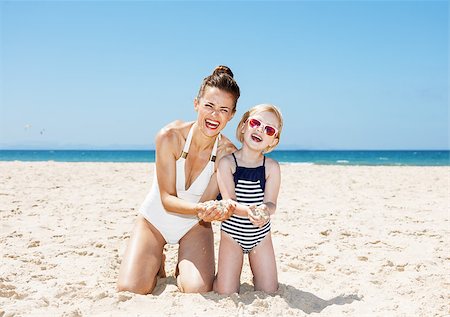 simsearch:400-06639191,k - Family fun on white sand. Happy mother and child in swimsuits at beach on a sunny day showing hands full of sand Stock Photo - Budget Royalty-Free & Subscription, Code: 400-08533638