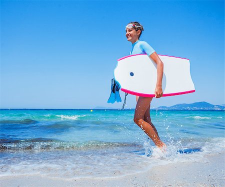 simsearch:400-07952891,k - Happy Surfing girl on a beach ready to go into the water. Sunset time. Stock Photo - Budget Royalty-Free & Subscription, Code: 400-08574076