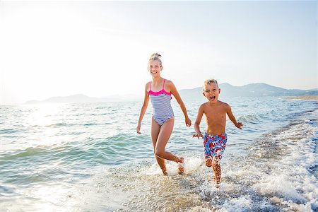 Happy brother and sister running at tropical beach against sunlight Foto de stock - Super Valor sin royalties y Suscripción, Código: 400-08574467