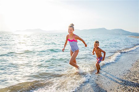 simsearch:400-04596901,k - Happy brother and sister running at tropical beach against sunlight Stock Photo - Budget Royalty-Free & Subscription, Code: 400-08574767