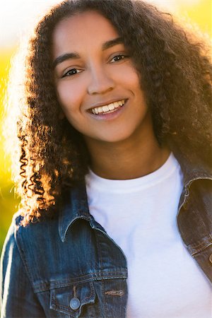 simsearch:400-04068097,k - Outdoor portrait of beautiful happy mixed race African American girl teenager female young woman smiling laughing with perfect teeth in golden evening sunshine Stockbilder - Microstock & Abonnement, Bildnummer: 400-08574880