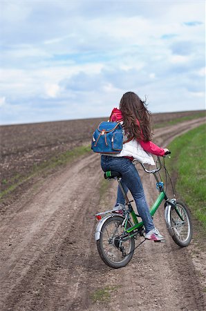 The girl goes on a bicycle on the road in a field Stockbilder - Microstock & Abonnement, Bildnummer: 400-08575078