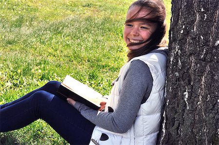 Girl reading a book sitting under a tree in the park Stockbilder - Microstock & Abonnement, Bildnummer: 400-08575306
