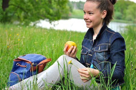 Girl with apple sitting on a picnic on the grass near the pond Stockbilder - Microstock & Abonnement, Bildnummer: 400-08575578