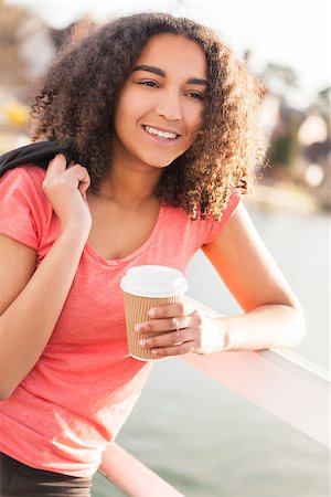 simsearch:400-04068097,k - Beautiful happy mixed race African American girl teenager female young woman with perfect teeth smiling drinking takeaway coffee outside Stockbilder - Microstock & Abonnement, Bildnummer: 400-08572975