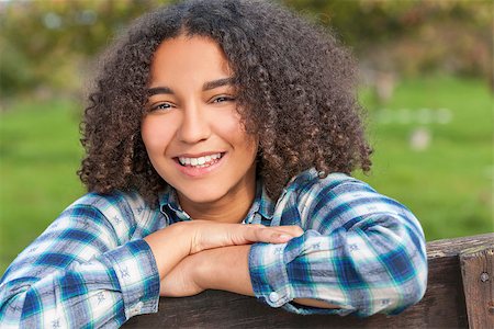 simsearch:400-04068097,k - Outdoor portrait of beautiful happy mixed race African American girl teenager female child resting on countryside fence smiling with perfect teeth Stockbilder - Microstock & Abonnement, Bildnummer: 400-08572978