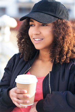 simsearch:400-04068097,k - Beautiful happy mixed race African American girl teenager female young woman smiling drinking takeaway coffee outside wearing black baseball cap and bomber jacket Stockbilder - Microstock & Abonnement, Bildnummer: 400-08572972