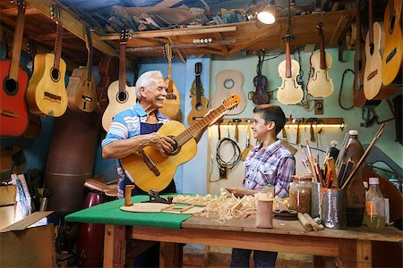 senior man playing guitar with child - Small family business and traditions: old grandpa with grandson in lute maker shop. The senior artisan gives teaches how to play classic guitar to the boy, who looks carefully at the instrument Stock Photo - Budget Royalty-Free & Subscription, Code: 400-08573812