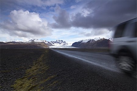 panoramic road drive - Horizontal photo of an off road car on a straight asphalt road coming from the mountains with clouds above and the Vatnajokull glacier in the background, Iceland Stock Photo - Budget Royalty-Free & Subscription, Code: 400-08614823