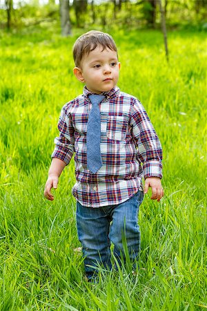 Little boy in the blue shirt jeans and striped tie walking in the grass in park Foto de stock - Super Valor sin royalties y Suscripción, Código: 400-08616776