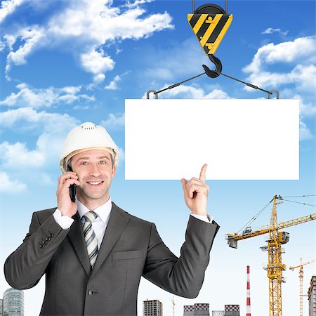 Smiling businessman in helmet talking on mobile with blank block on building site Stock Photo - Budget Royalty-Free & Subscription, Code: 400-08617342