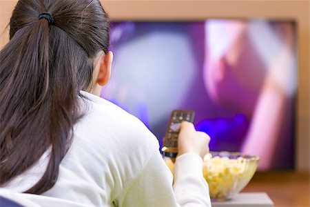 Teenager girl with remote control watching tv and eating popcorn. Foto de stock - Super Valor sin royalties y Suscripción, Código: 400-08621216