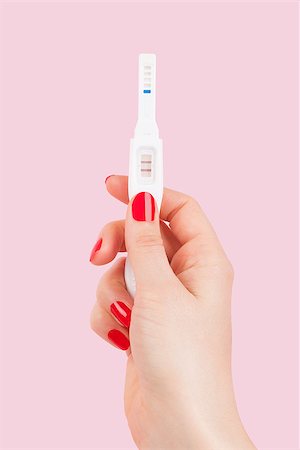 Beautiful female hand with red fingernails holding positive pregnancy test isolated on pink background. Motherhood, pregnancy, birth control concept. Minimal sparse modern image language. Stock Photo - Budget Royalty-Free & Subscription, Code: 400-08621756