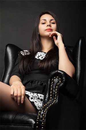 portrait of beautiful young woman in big black leather armchair over dark background Stock Photo - Budget Royalty-Free & Subscription, Code: 400-08669756