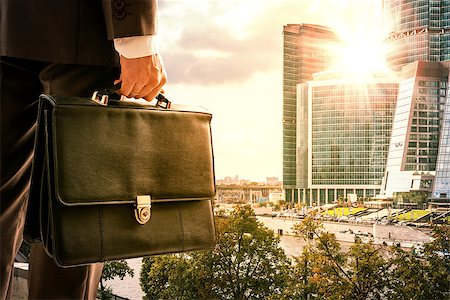 Businessman with suitcase against modern city, rear view Stock Photo - Budget Royalty-Free & Subscription, Code: 400-08670275