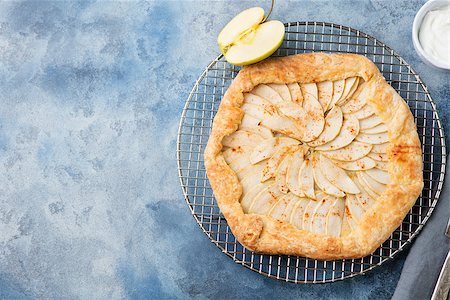 Apple galette, pie, tart with cinnamon on cooling rack on a blue stone background. Top view Photographie de stock - Aubaine LD & Abonnement, Code: 400-08670410