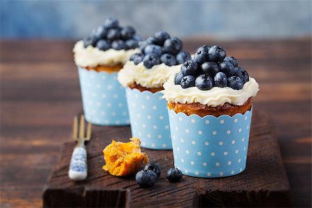Pumpkin cupcakes decorated with cream cheese frosting and fresh blueberries on a wooden background Copy space Foto de stock - Super Valor sin royalties y Suscripción, Código: 400-08671084