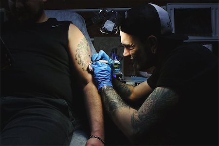 simsearch:400-04190246,k - Beautiful tattooist with tunnels makes a tattoo on his leg Foto de stock - Super Valor sin royalties y Suscripción, Código: 400-08671562