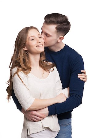 Portrait of young man kissing his girlfriend while hugging her.Girl smiling with eyes closed. Fotografie stock - Microstock e Abbonamento, Codice: 400-08694436