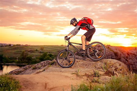 simsearch:400-09132505,k - Cyclist Riding the Bike Down Hill on the Mountain Rocky Trail at Sunset. Extreme Sports Foto de stock - Super Valor sin royalties y Suscripción, Código: 400-08695391