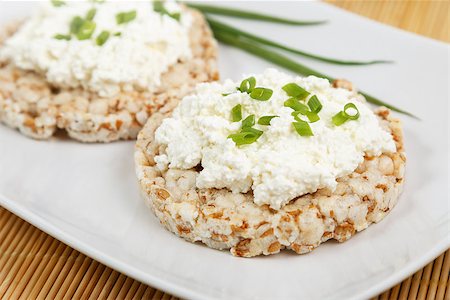 crisp breads with cottage cheese and onion choppes in rings on the white plate on the bamboo napkin Stockbilder - Microstock & Abonnement, Bildnummer: 400-08695958