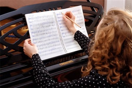 simsearch:400-09115438,k - Young woman musician writes in music book pencil. Sitting in front of grand piano. Foto de stock - Super Valor sin royalties y Suscripción, Código: 400-08693427