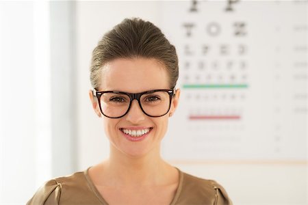 simsearch:400-05381013,k - Modern health care. Smiling young woman wearing eyeglasses in front of Snellen chart Photographie de stock - Aubaine LD & Abonnement, Code: 400-08693808
