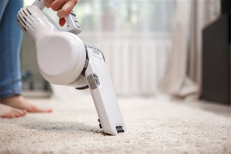 simsearch:400-04640043,k - Woman cleaning carpet modern white wireless rechargeable vacuum cleaner idoors Stock Photo - Budget Royalty-Free & Subscription, Code: 400-08706535